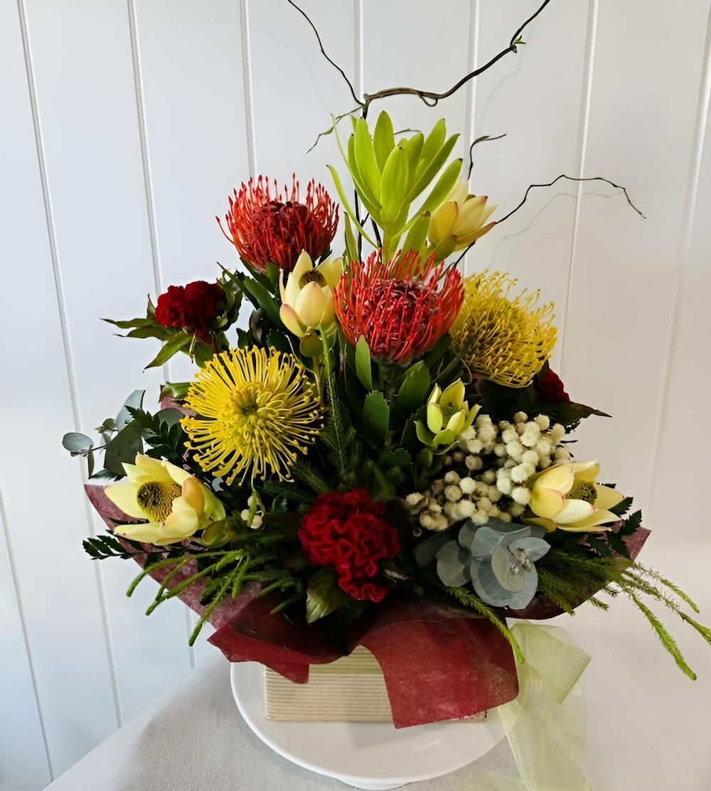 A Bouquet of Flowers in a Wooden Box on a Table — Bundaberg House of Flowers In Coral Cove, QLD