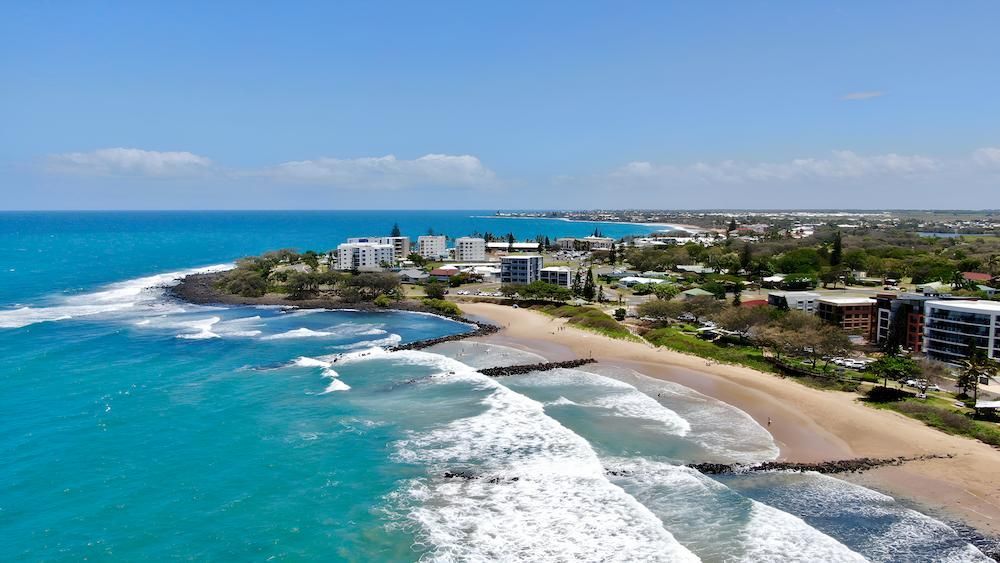 An Aerial View of a Beach With Waves Crashing on the Shore — Bundaberg House of Flowers In Bargara, QLD