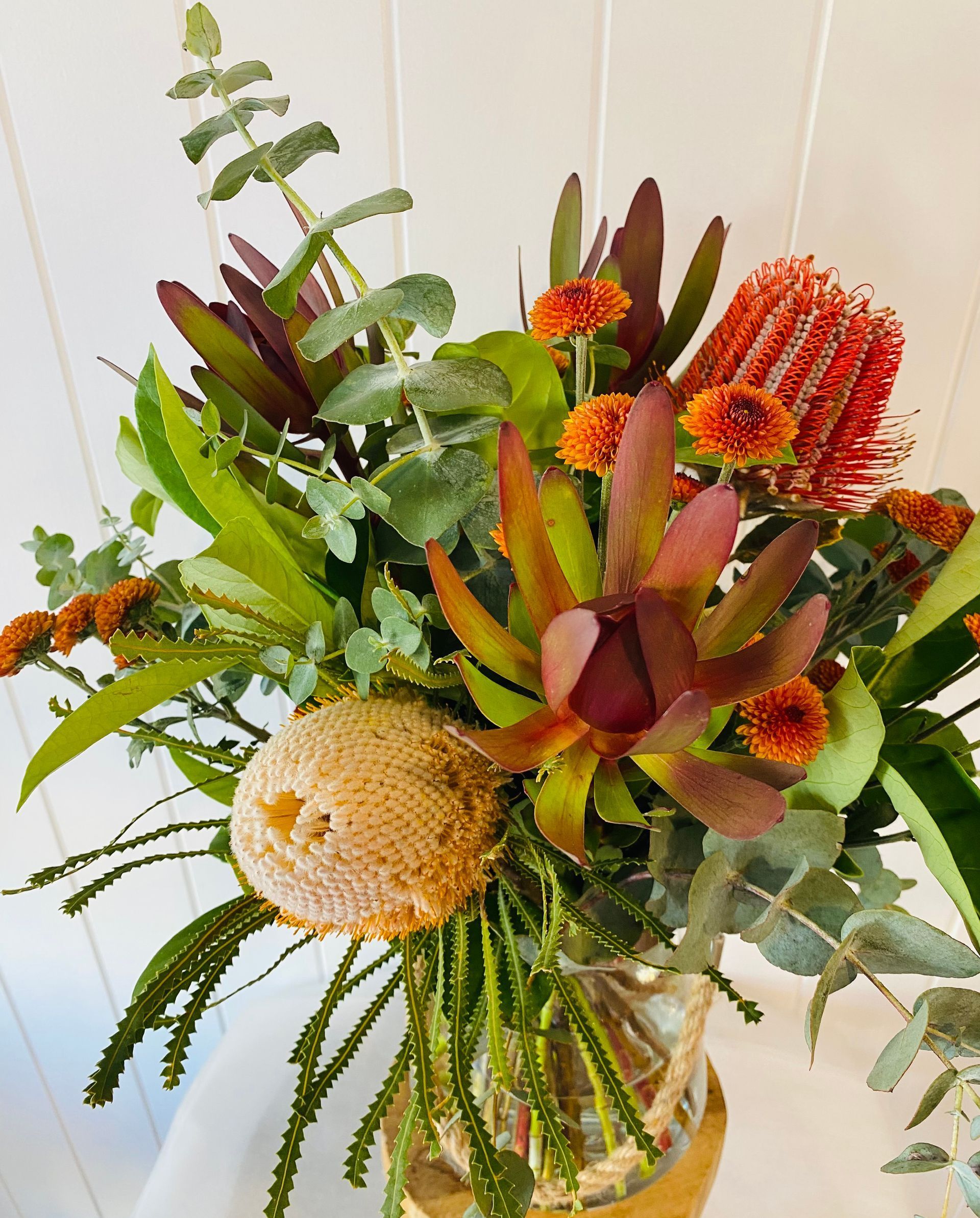 A Vase Filled With Flowers and Leaves is Sitting on a Table — Bundaberg House of Flowers in Bundaberg West, QLD