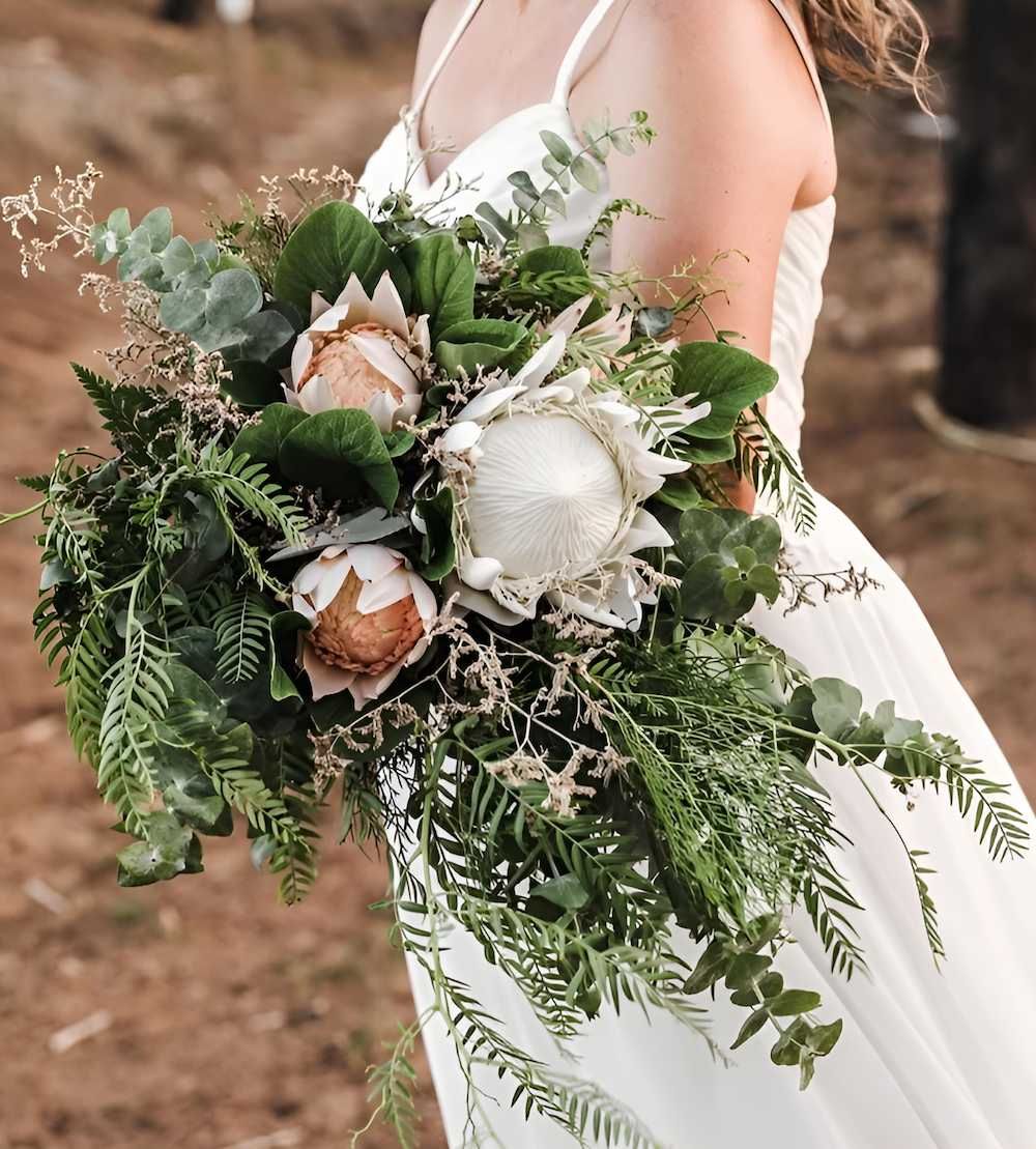 A Woman in a White Dress is Holding a Bouquet of Flowers — Bundaberg House of Flowers In Moore Park Beach, QLD