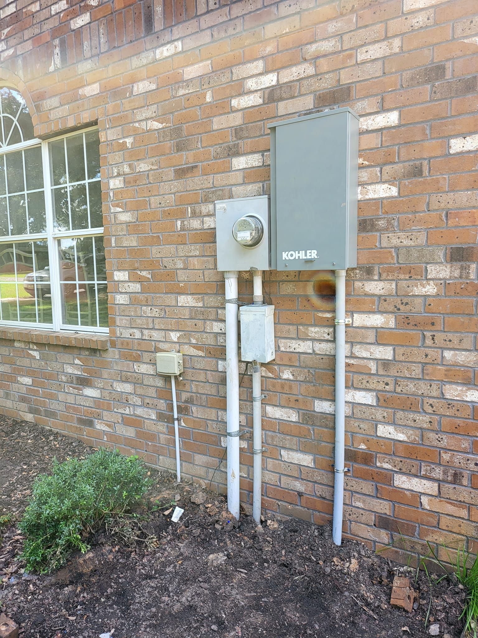A brick wall with a box on it and a window.