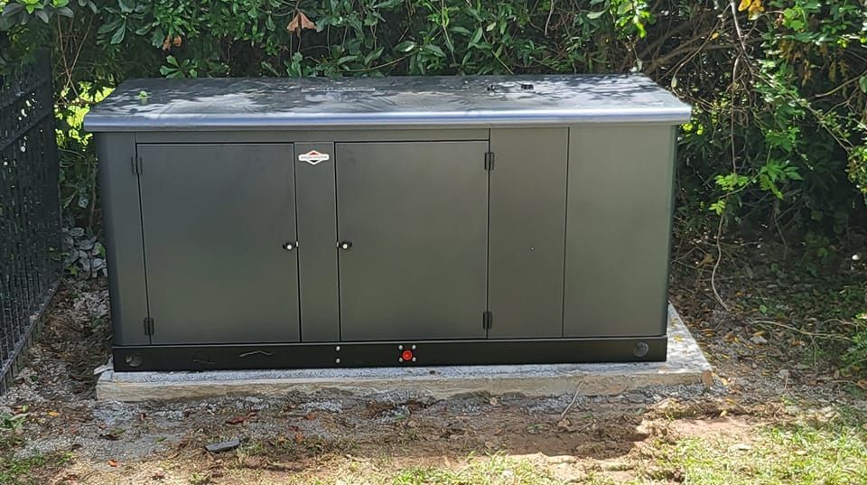 A black box is sitting in the grass next to a fence.