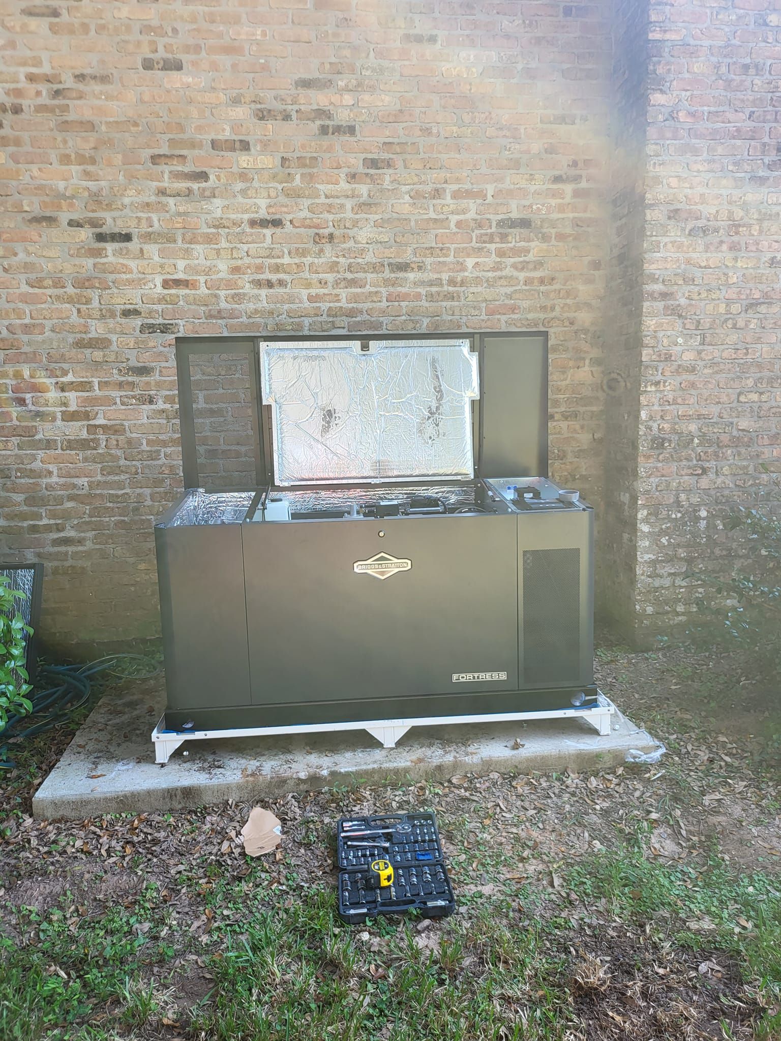 A large black box is sitting in front of a brick building.