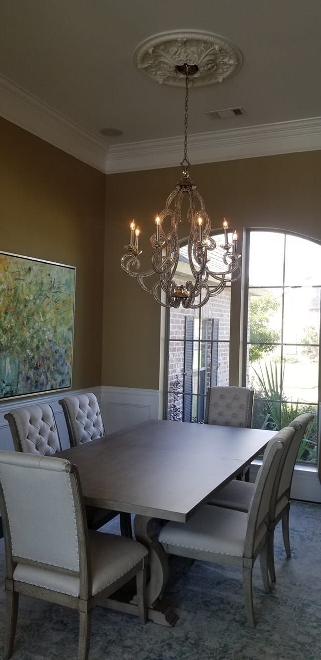 A dining room with a table and chairs and a chandelier hanging from the ceiling.