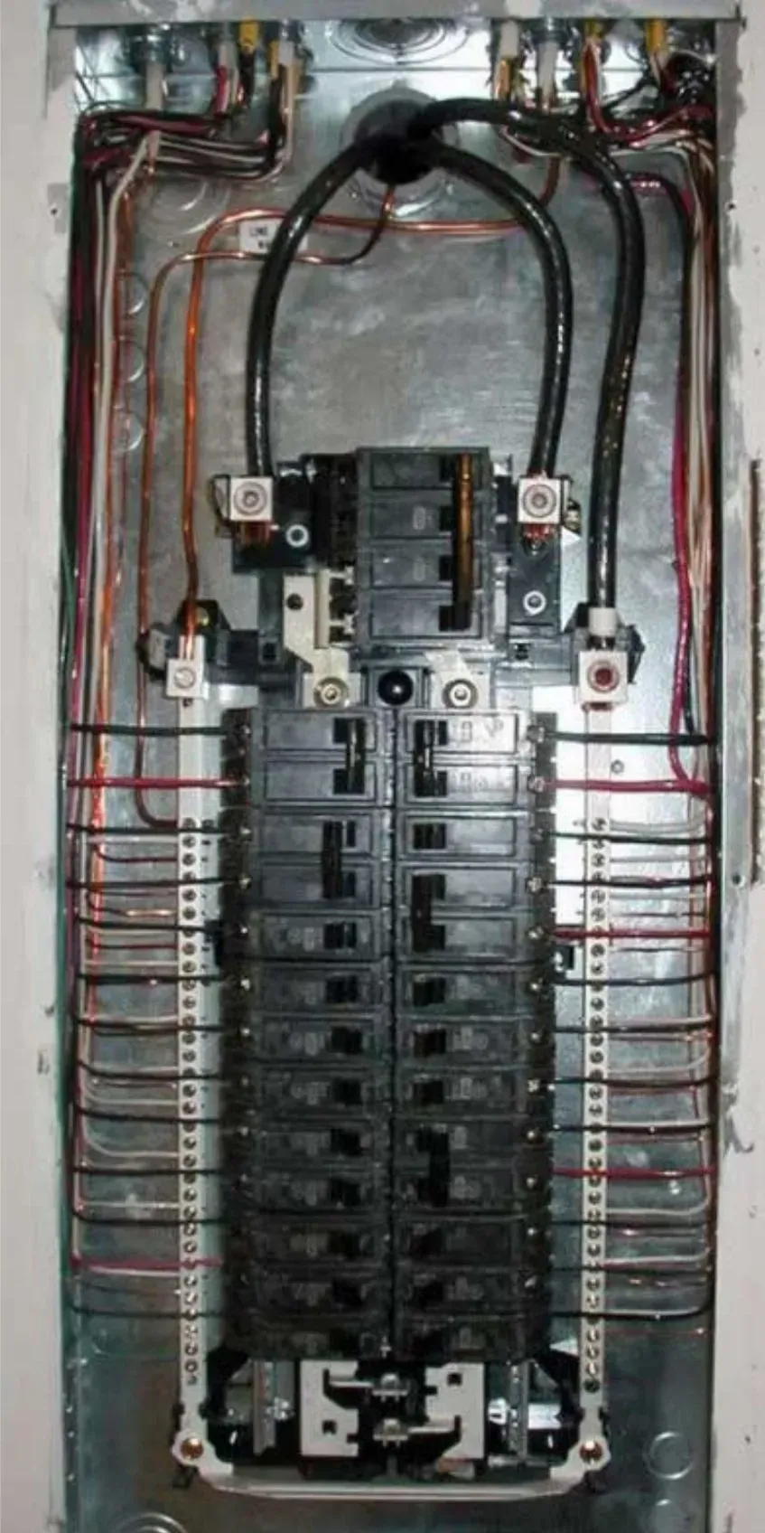 A close up of a electrical panel with a lot of wires coming out of it.