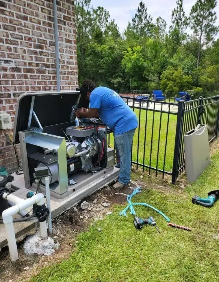 A man is working on a generator outside of a house.