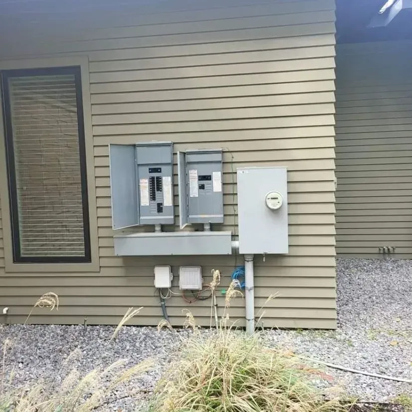 A house with a lot of electrical boxes on the side of it.