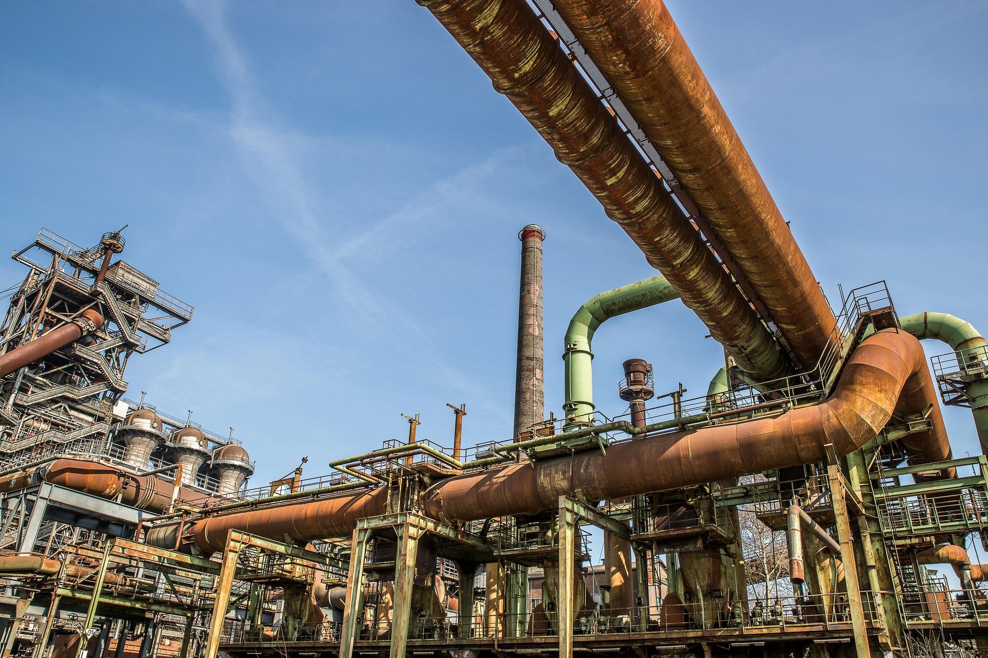 A factory with a lot of pipes and chimneys and a blue sky in the background.