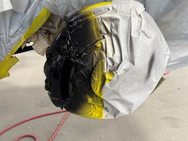 A car wheel is being painted black and yellow.