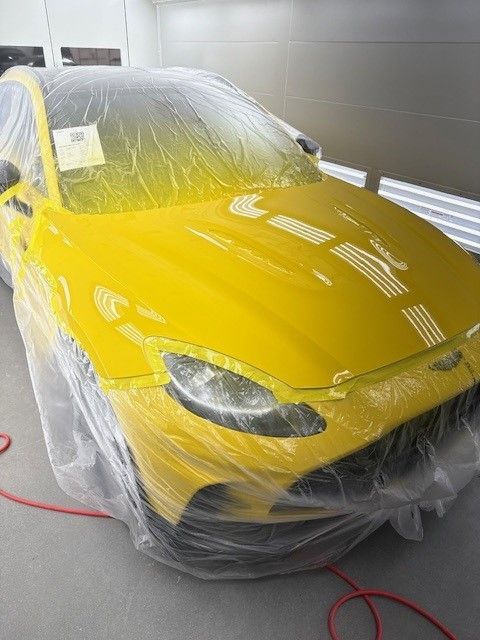 A yellow car is wrapped in plastic and sitting in a garage.