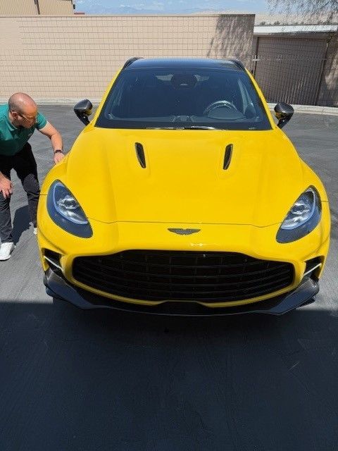 A man is kneeling next to a yellow sports car.