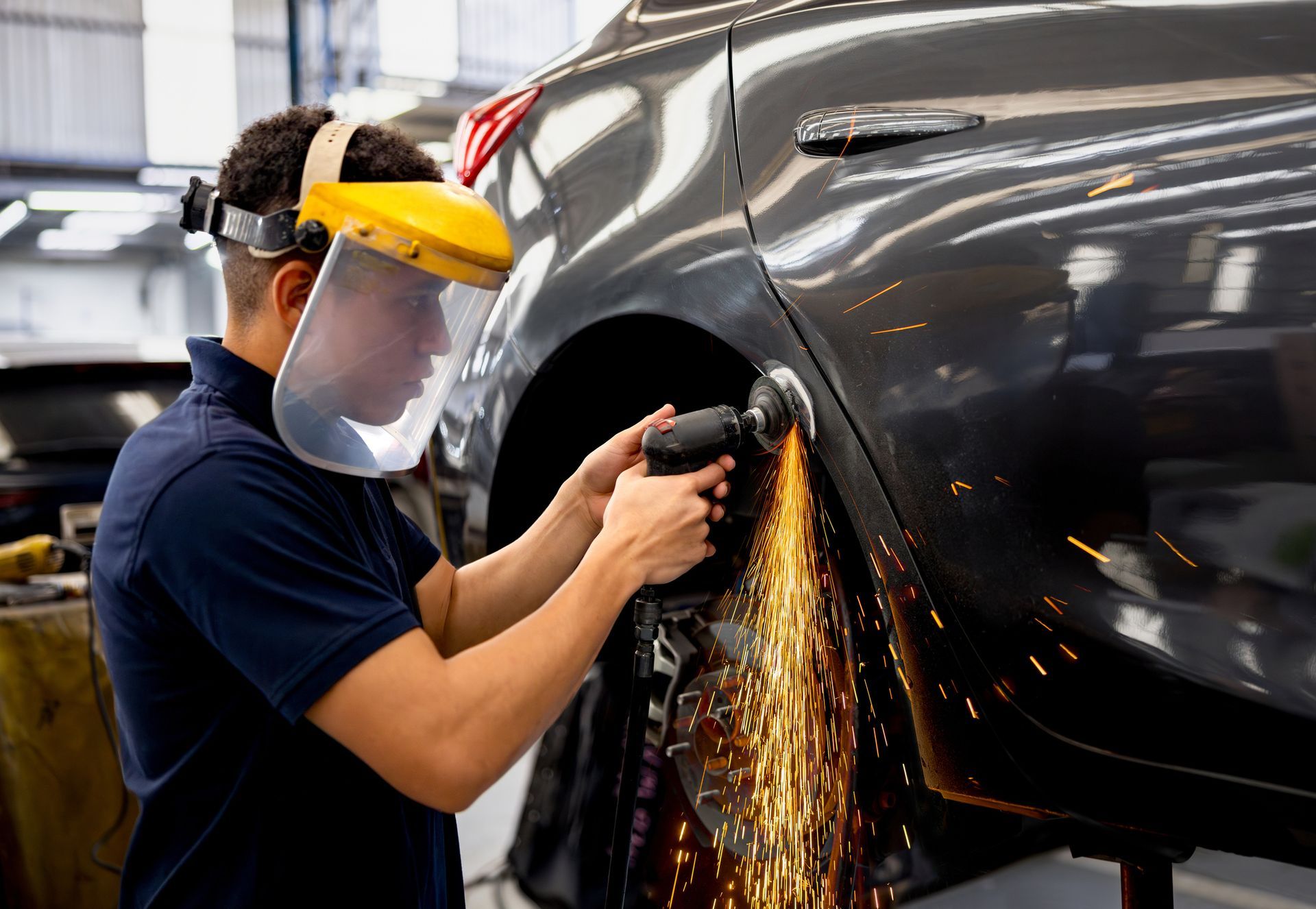 Mechanic grinding a car while working at an auto repair shop. Mechanic grinding a car while working at an auto repair shop.