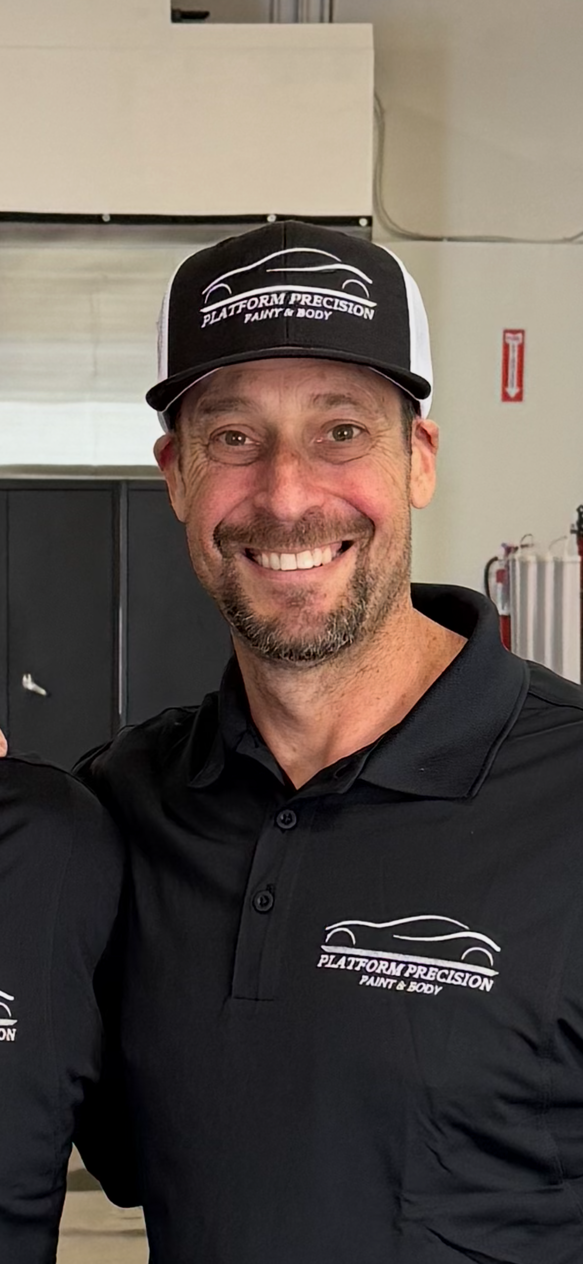 Man in black shirt and hat smiles at the camera.