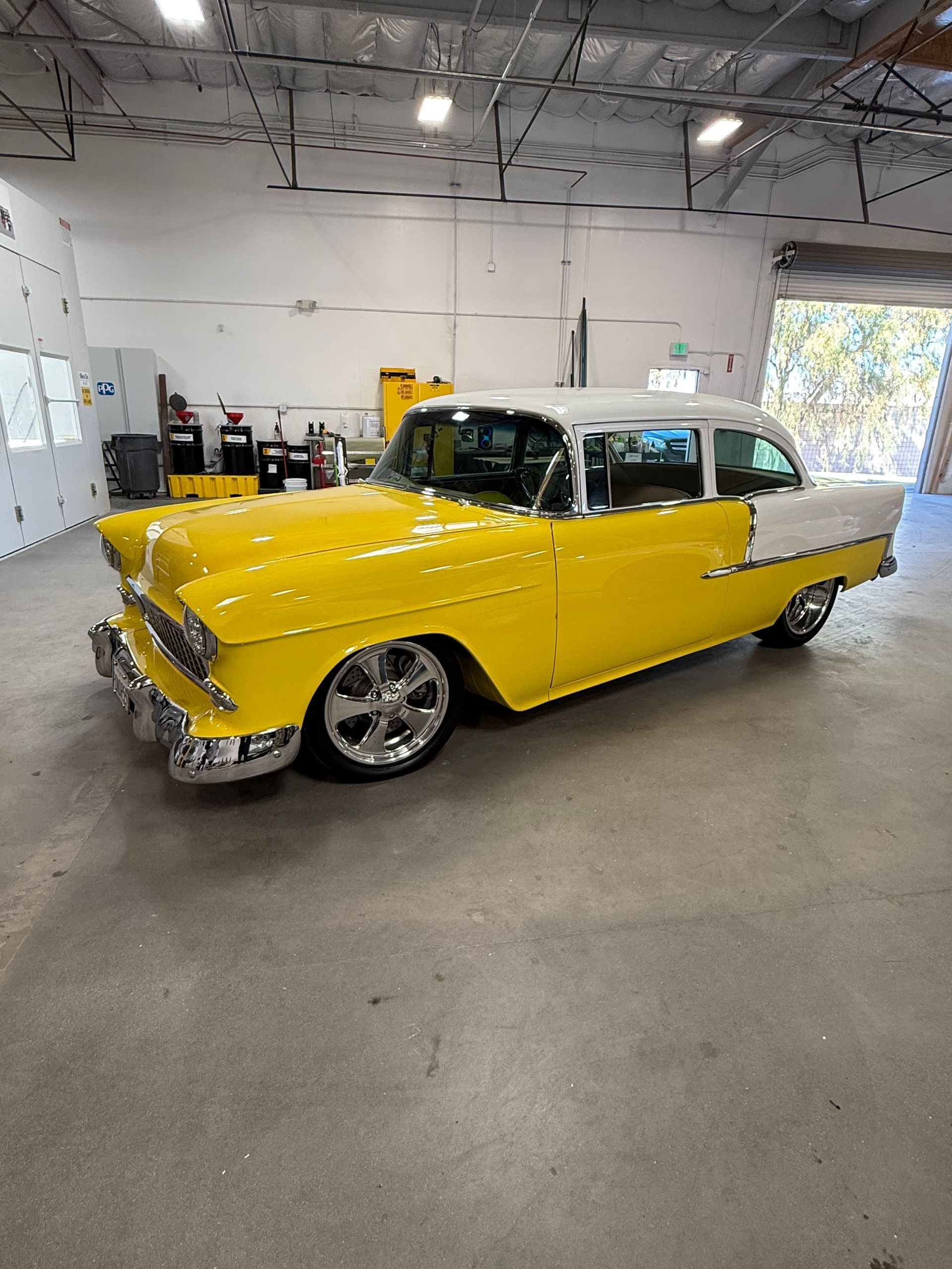 Yellow and white classic car in a garage with chrome wheels.