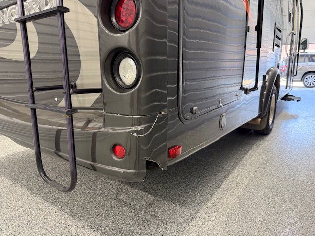 Gray RV with ladder and damage to the rear bumper.