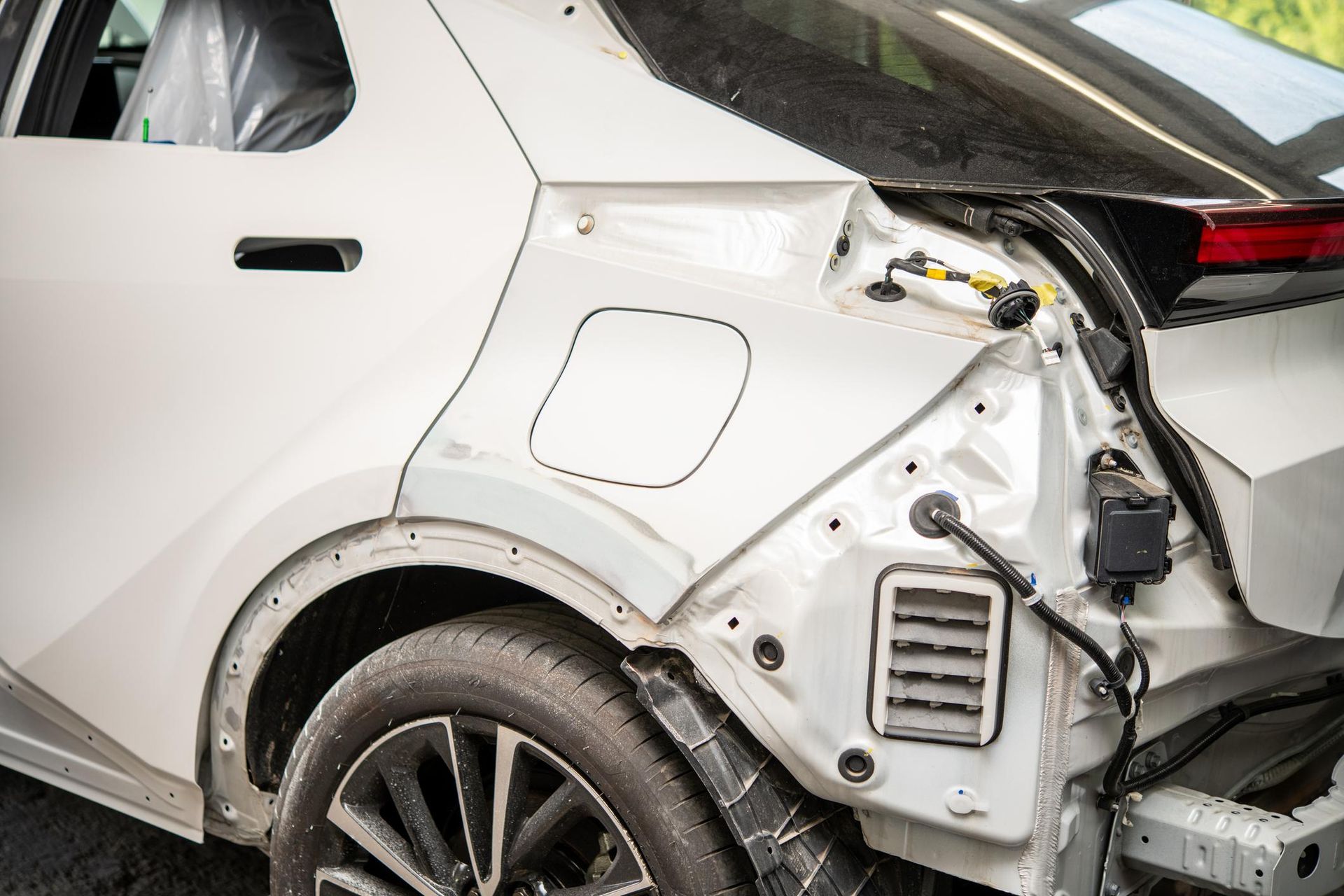 White car rear quarter panel undergoing repair, revealing structural components.