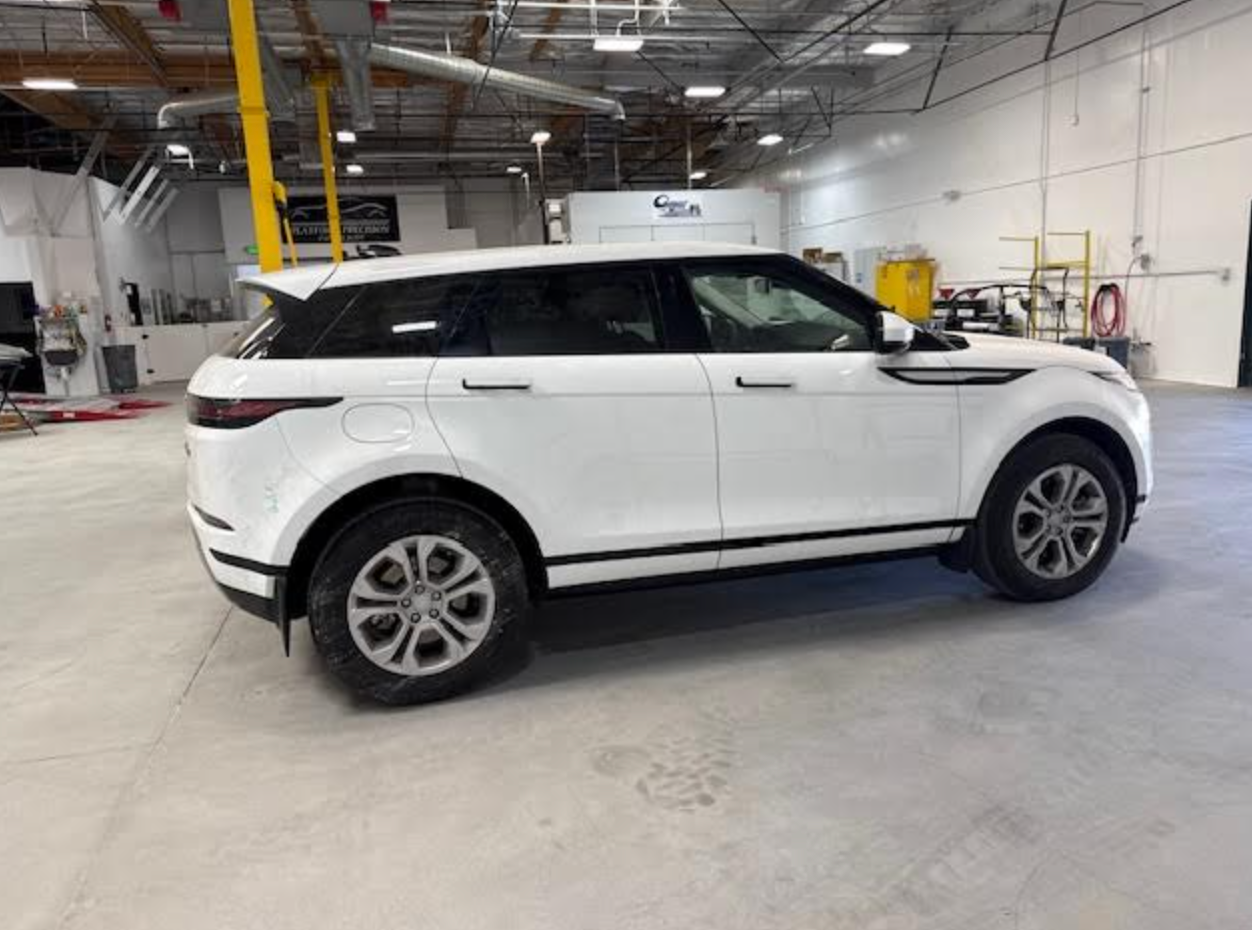 A white range rover evoque is parked in a garage.