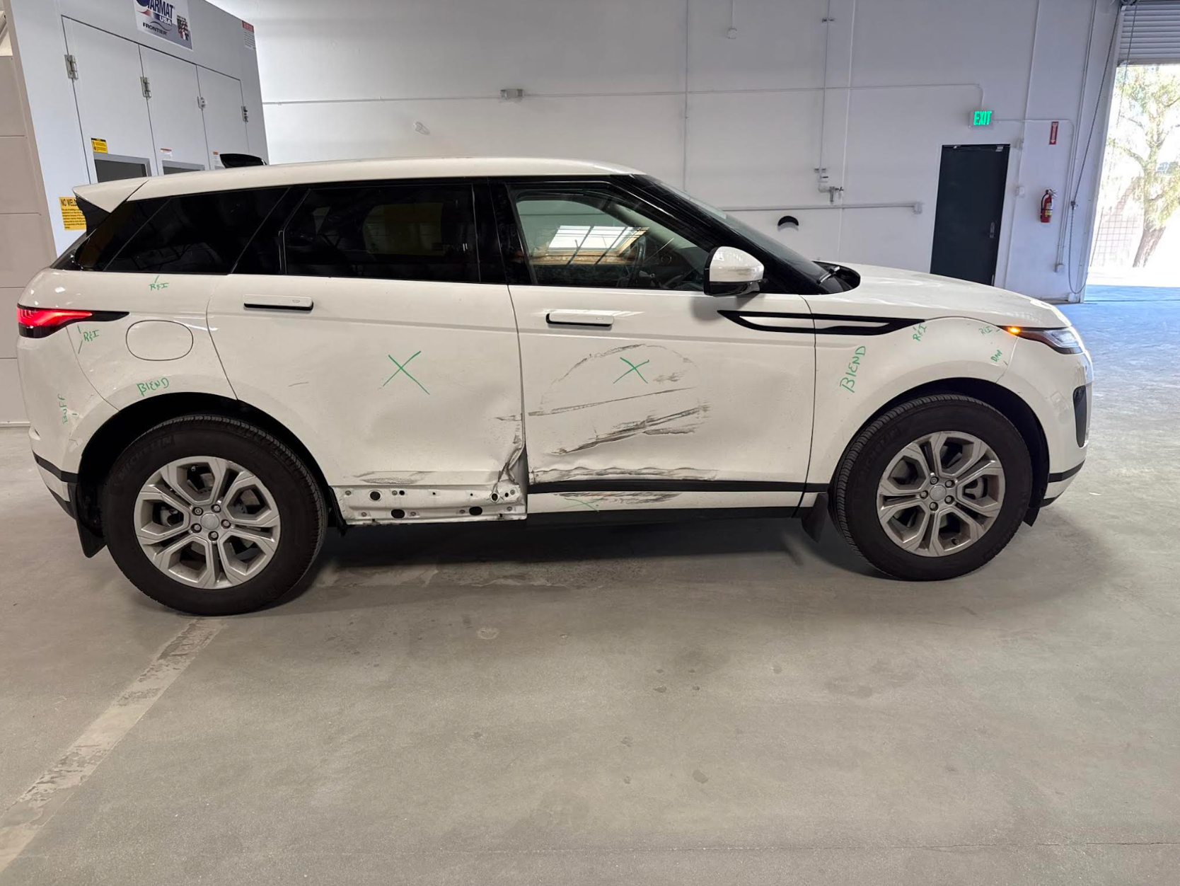A white range rover evoque is parked in a garage.