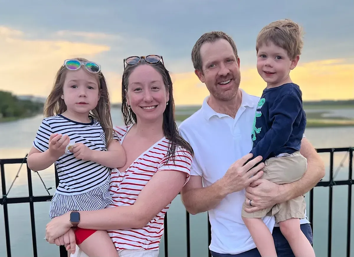 The family of Attorney Andrew Smith is posing for a picture on a bridge overlooking a body of water.