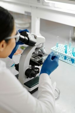 A woman is looking through a microscope in a laboratory.