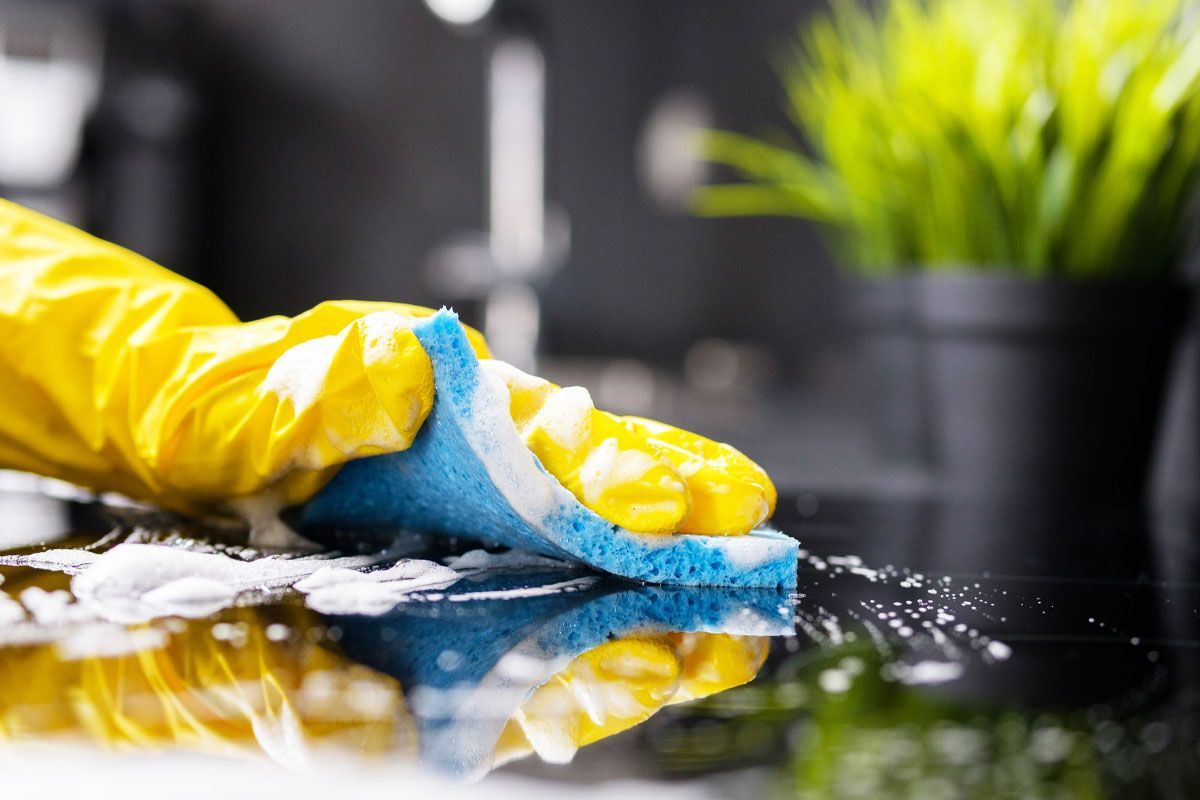 Person using a squeegee to clean a mirror, removing streaks and water droplets, to reveal a clear and reflective surface.