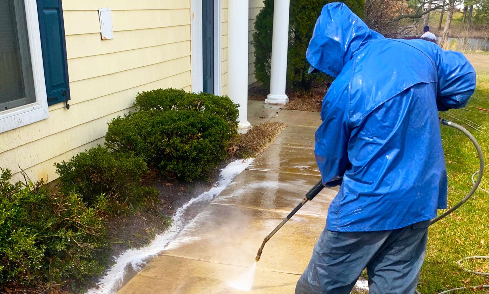 Person using a squeegee to clean a mirror, removing streaks and water droplets, to reveal a clear and reflective surface.