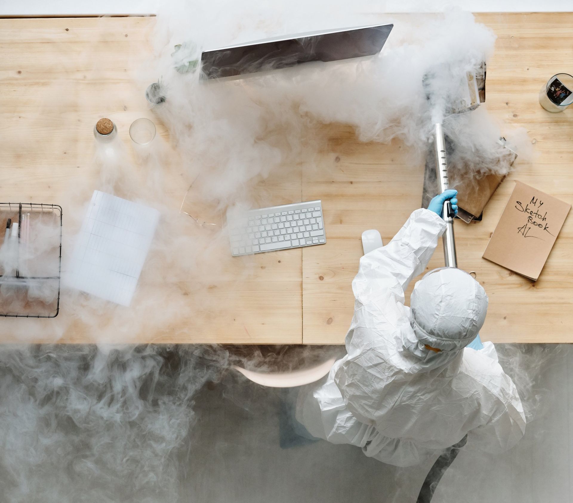 An office cleaner in a full protective suit diligently sanitizing the workspace, ensuring a safe and hygienic environment.