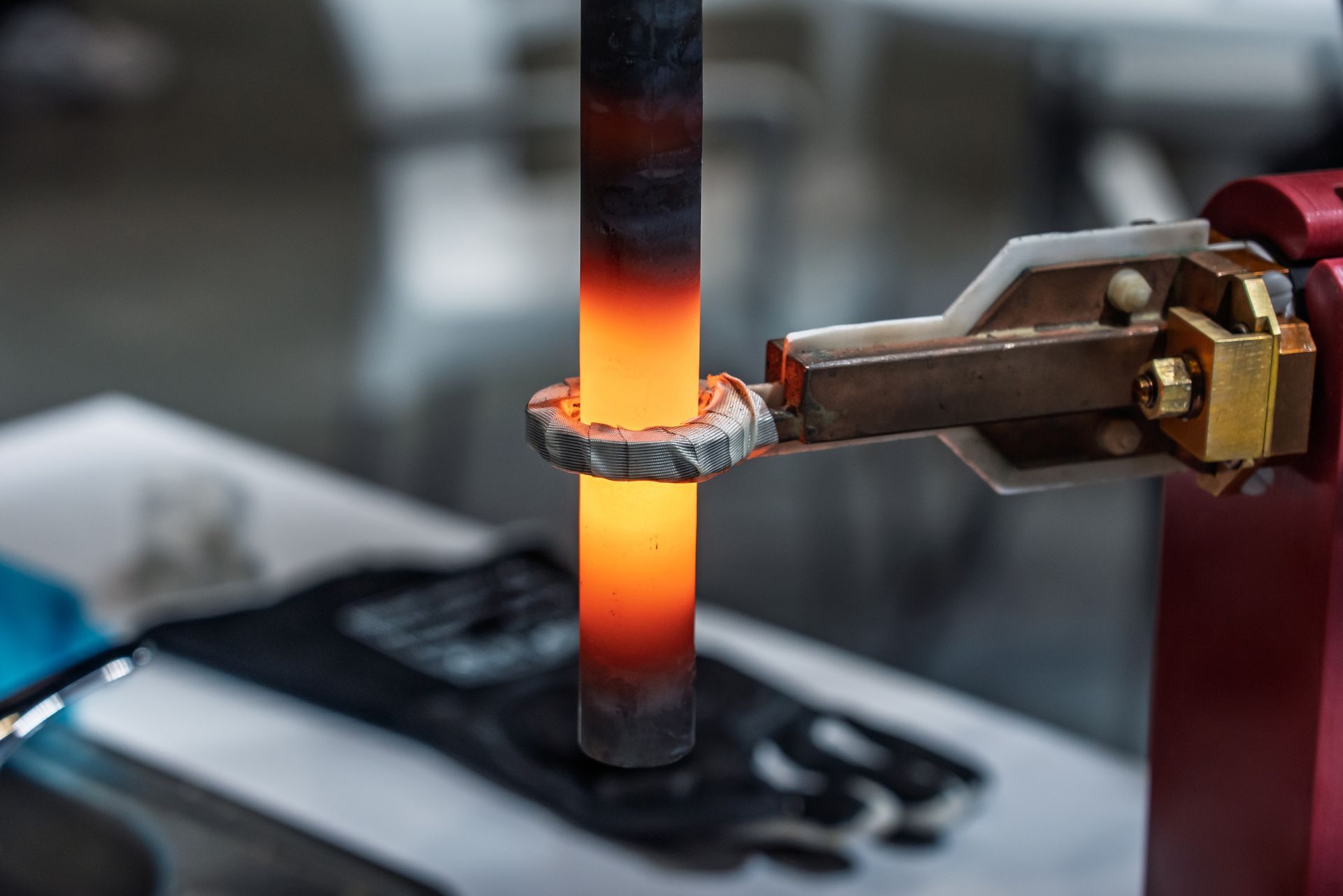 Tige métallique incandescente chauffée par une machine, maintenue par une pince.