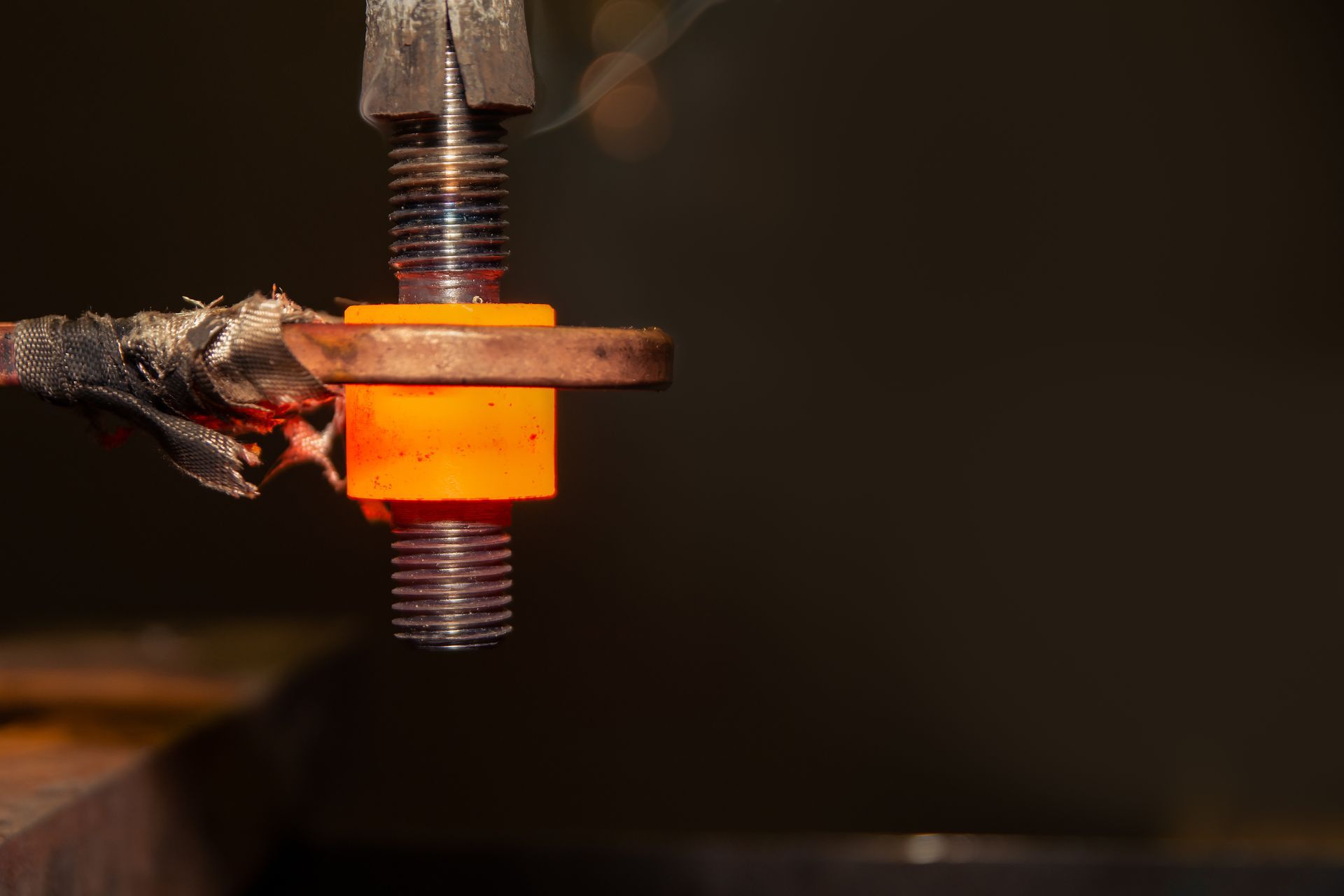 Plastique orange entre deux boulons chauds, avec de la fumée s'élevant.