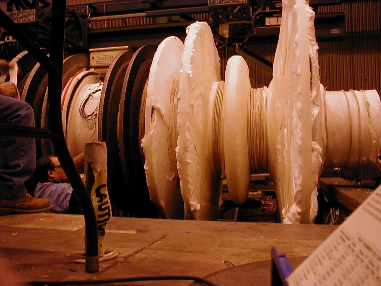 Grande turbine industrielle avec isolation blanche, une personne est assise à proximité.