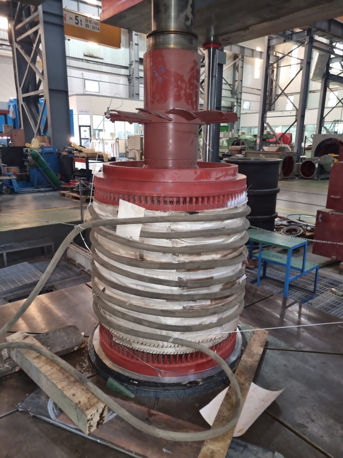 Grand composant industriel, rouge et argent, en cours de fabrication en usine.