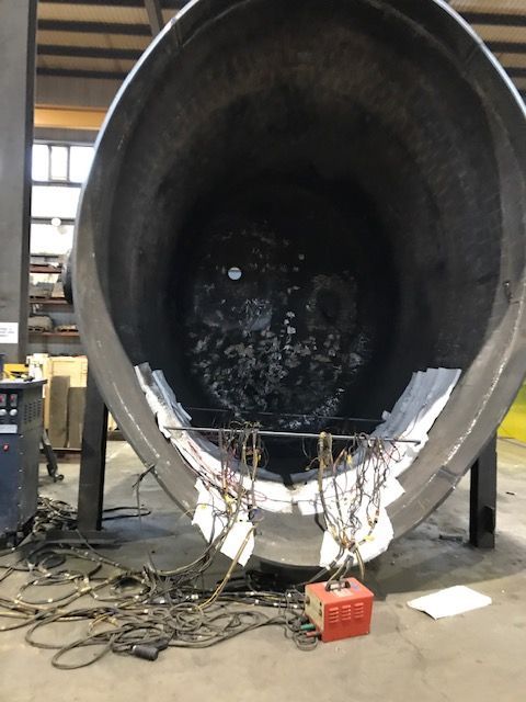 À l'intérieur d'un grand réservoir en acier sombre, avec des fils attachés et un appareil rouge, décor industriel.