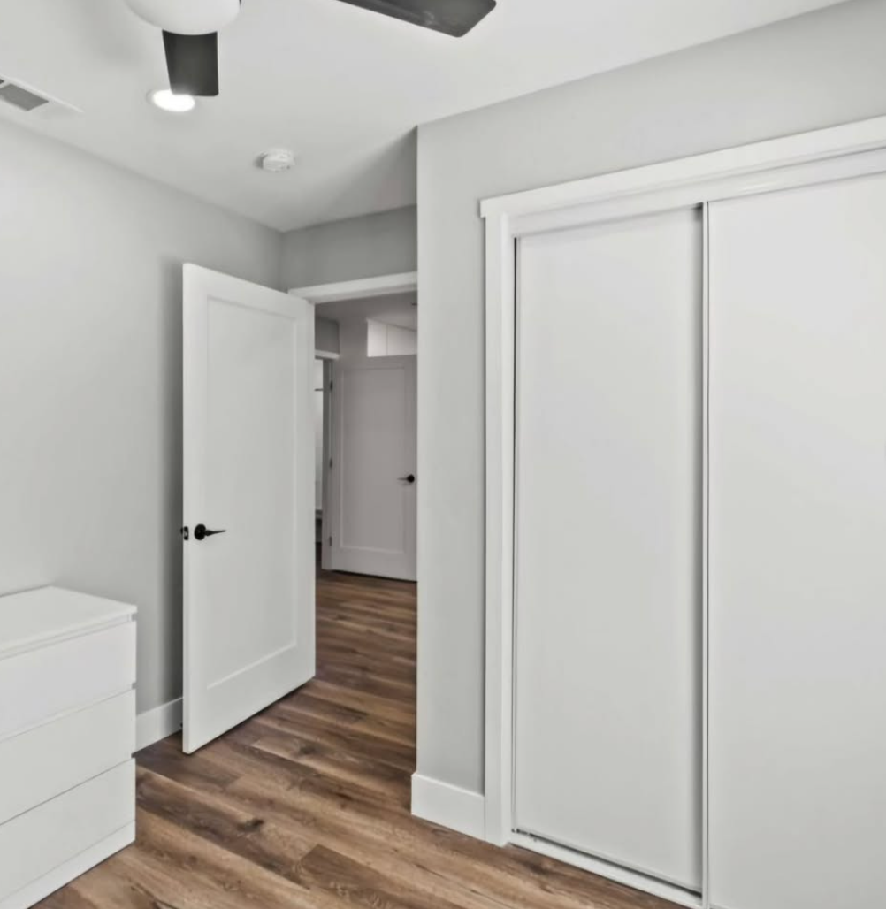 A bedroom with a closet and a ceiling fan