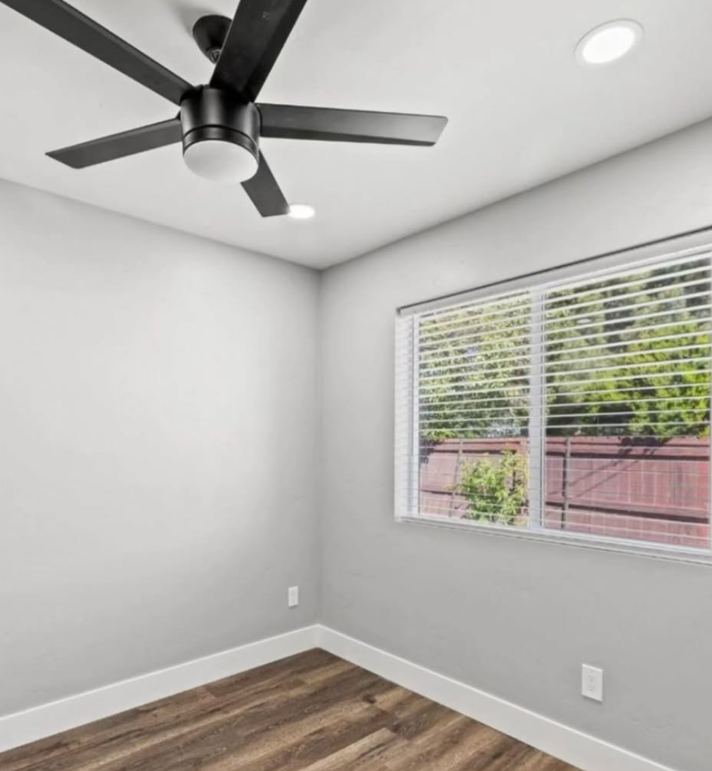 An empty room with a ceiling fan and a window