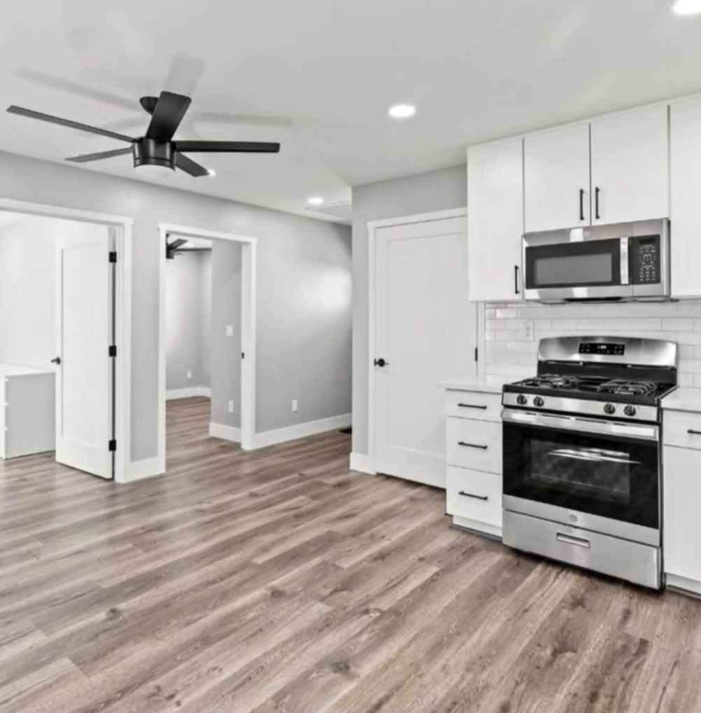 A kitchen with a stove , microwave , and ceiling fan.