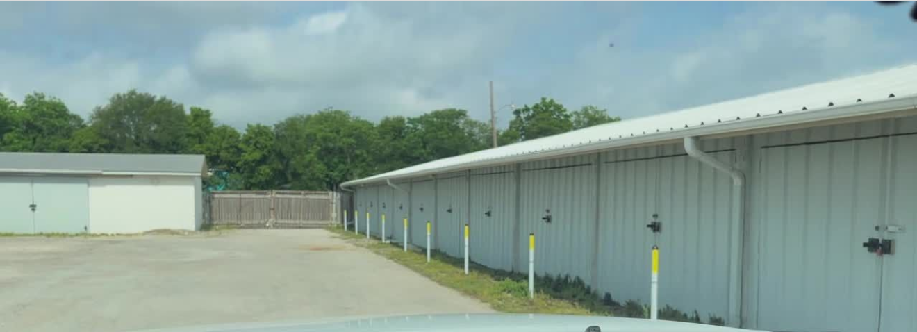 A row of white buildings are lined up next to each other on a dirt road.