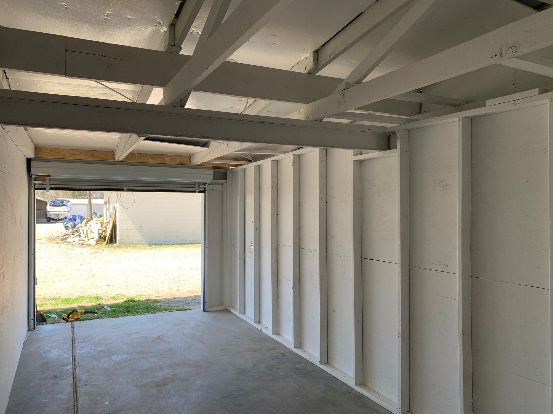 The inside of a garage with the door open and a concrete floor.