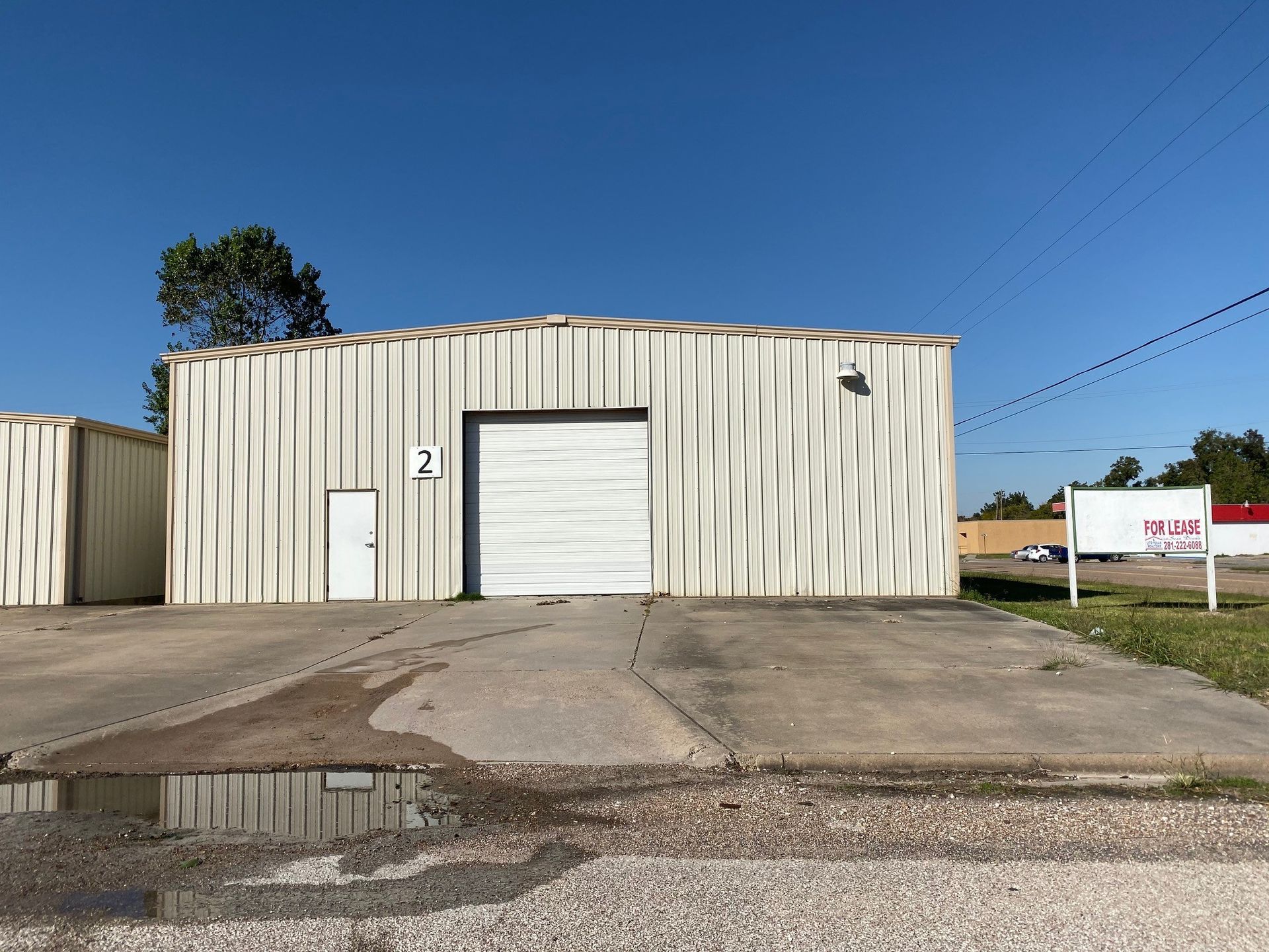 A white building with a white garage door is sitting on the side of the road.