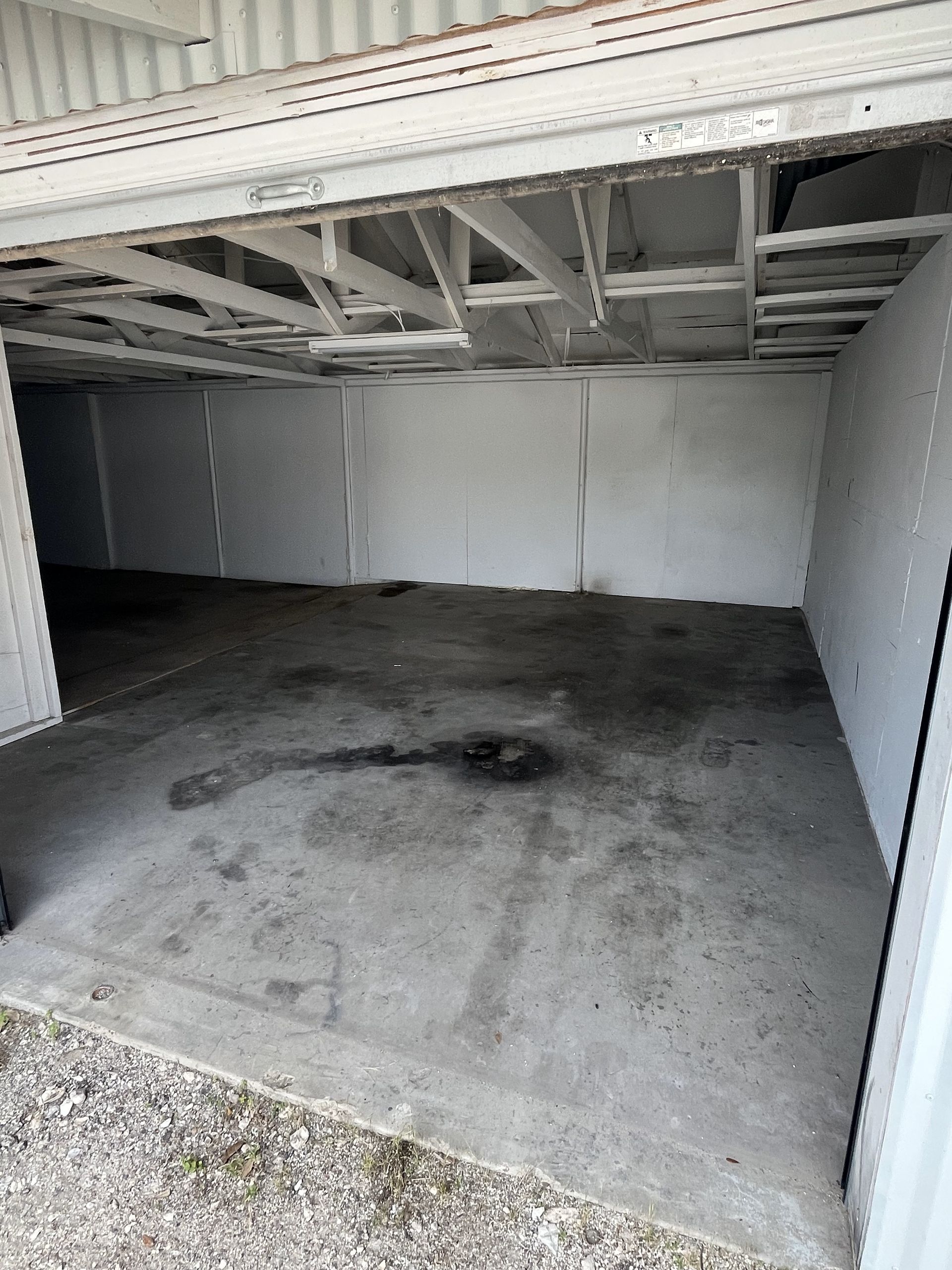 An empty garage with the door open and a concrete floor.