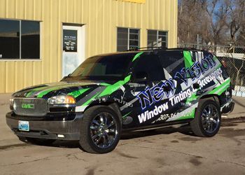 a green and black van is parked in front of a building .