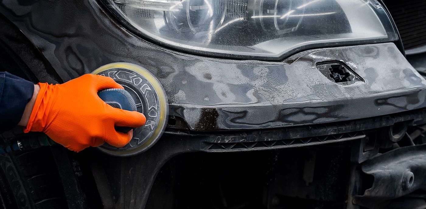 Blue sports car driving on a road, trees in the background, daytime.