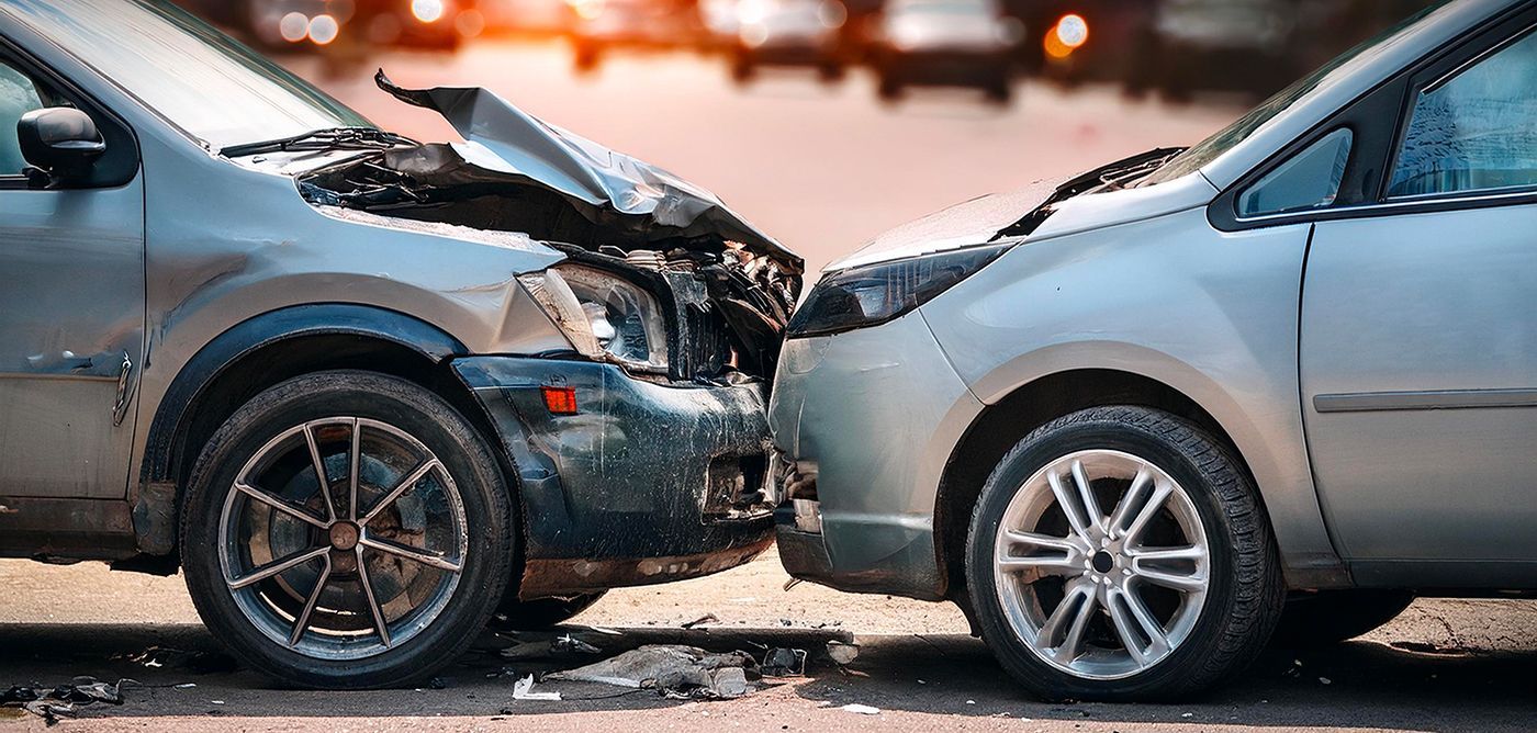 Two cars involved in a head-on collision. The front of the darker car is severely damaged.
