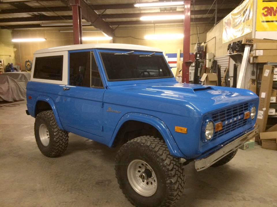 A blue and white bronco is parked in a garage
