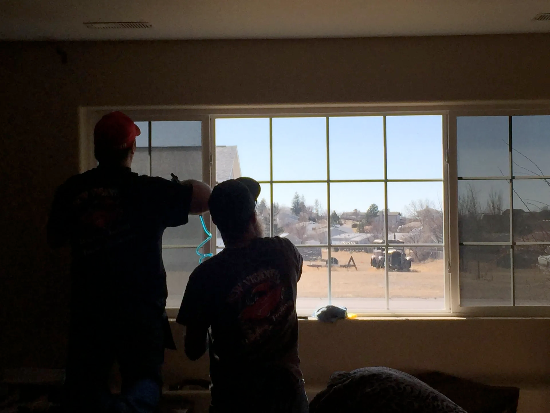 Two men are standing in front of a large window