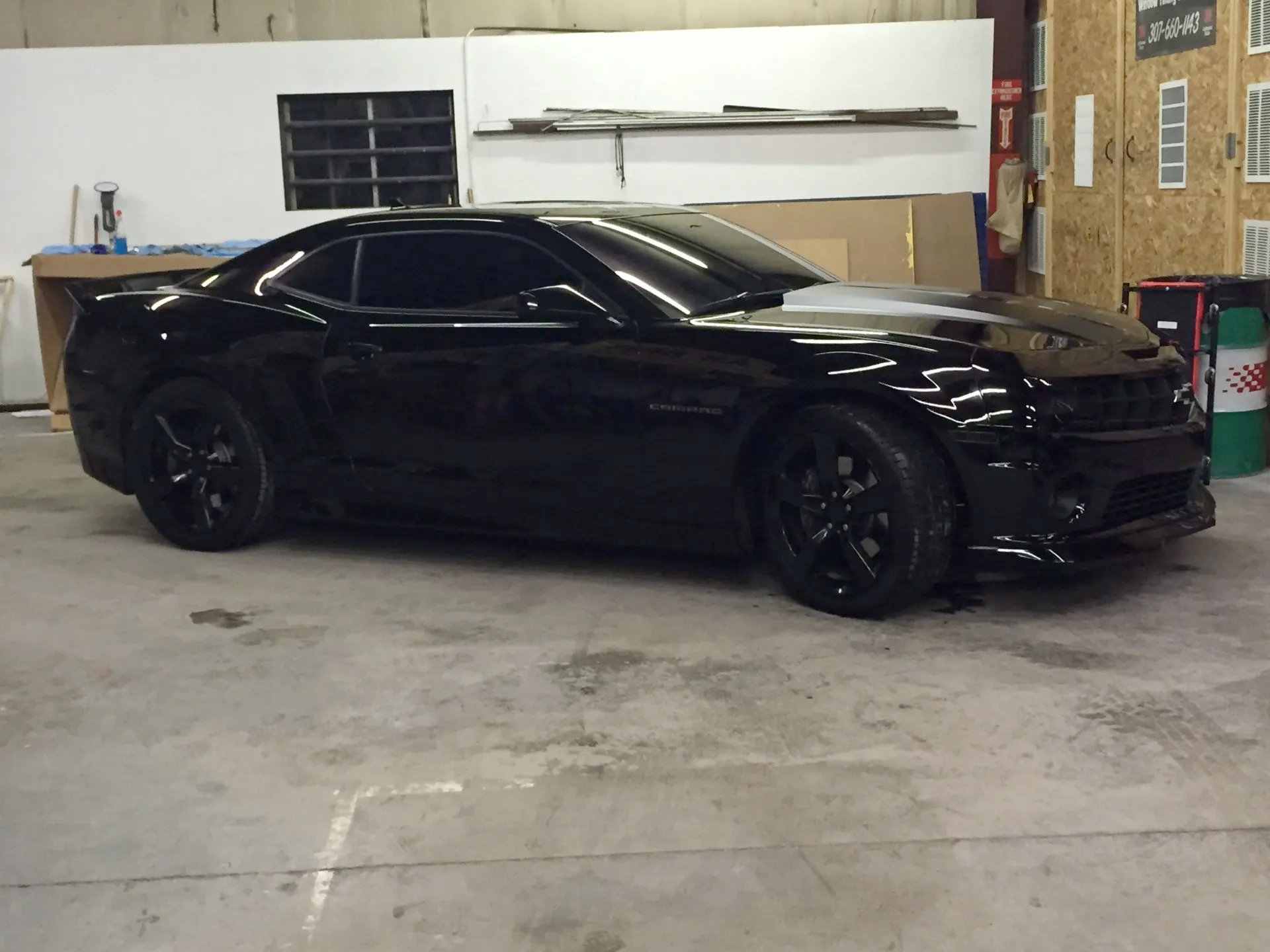 A black sports car is parked in a garage