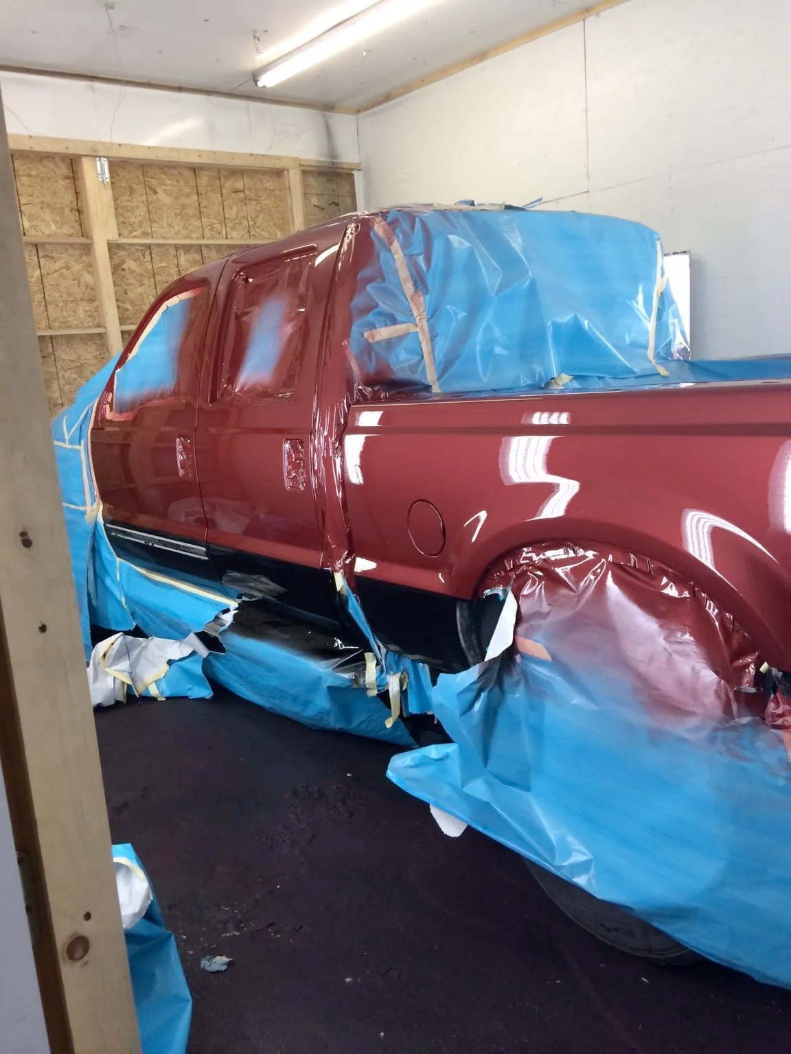 A red truck is being painted in a garage