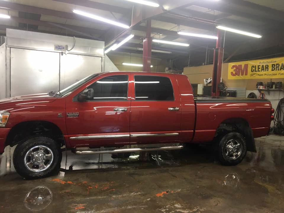 A red truck is parked in a garage next to a 3m sign.