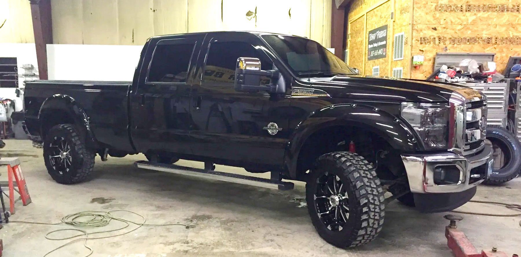 A black truck is parked in a garage next to a tire.