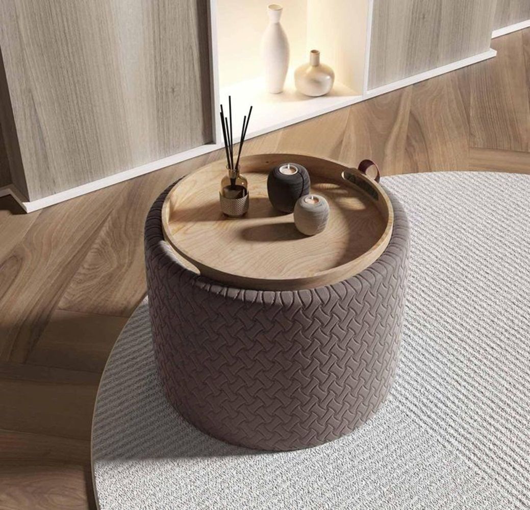 Pouf rotondo con vassoio in legno contenente candele e decorazioni, adagiato su un tappeto testurizzato.