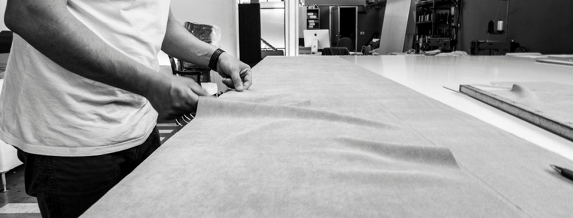 Una persona taglia un tessuto su un grande tavolo. L'ambientazione sembra quella di un laboratorio.